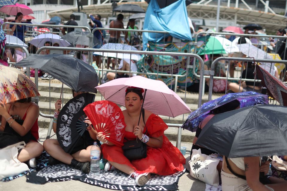 A girl using a fan waits among other people before the Taylor Swift concert, following the death of a fan due to the heat during the first day concert, in Rio de Janeiro, Brazil, November 18, 2023. REUTERS/Pilar Olivares



