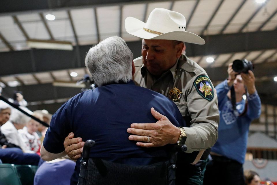 Uvalde County Sheriff Ruben Nolasco embraces Texas Governor Greg Abbott as they attend a vigil a day after a gunman killed 19 children and two teachers at Robb Elementary School, at Uvalde County Fairplex Arena, in Uvalde, Texas, U.S. May 25, 2022. REUTERS/Marco Bello