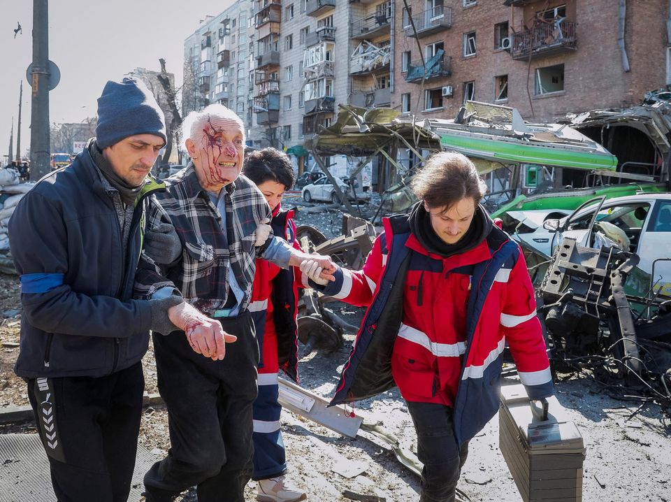 People and medics help a wounded resident of a house destroyed by shelling as Russia's attack on Ukraine continues, in Kyiv, Ukraine