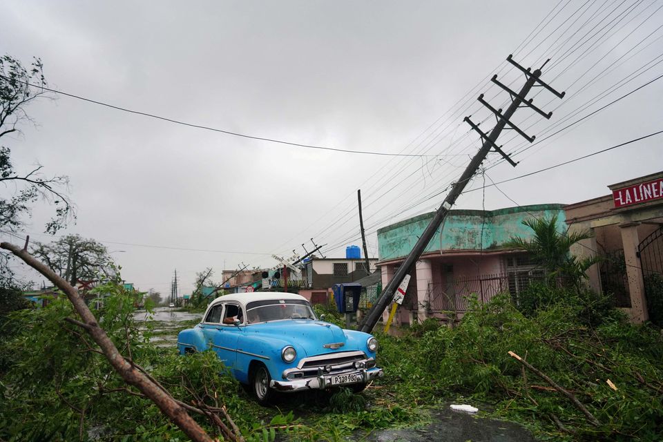 A vintage car passes by debris caused by the Hurricane Ian as it hit Pinar del Rio, Cuba. Reuters