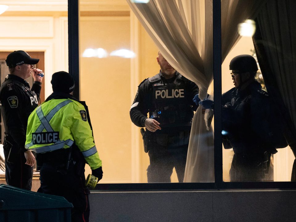 Police stand in the lobby of a condominium building following a shooting in Vaughan, Ontario, Sunday, Dec. 18, 2022. Authorities said multiple people were shot and killed in a unit of the building in the Toronto suburb and the gunman was killed by police. (Arlyn McAdorey/The Canadian Press via AP)