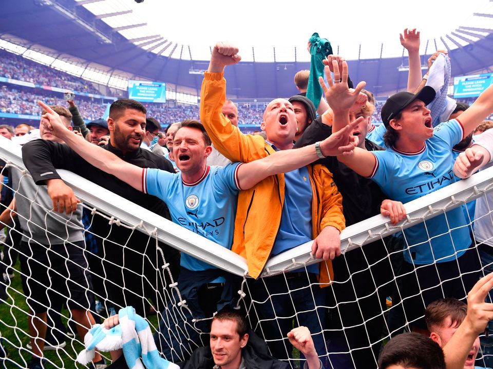 Manchester City fans celebrate on the pitch in the net of the goal after their side finished the season as Premier League champions. (Photo by Stu Forster/Getty Images)