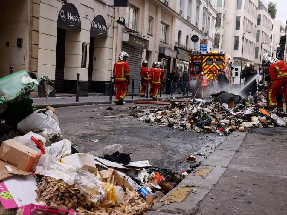 Firemen controlling the remains of a garbage fire from last night protests against the retirement bill in Paris, Friday, March 24, 2023. (AP Photo/Thomas Padilla)