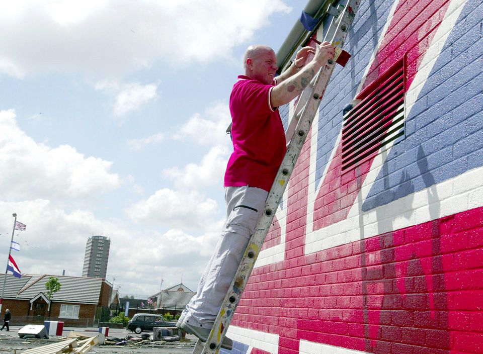 Джонни Адэр рисует флаг Союза на фронтоне здания.