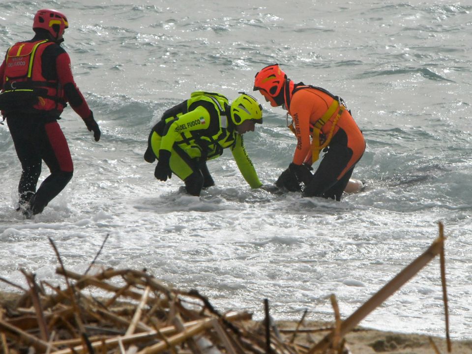 Rescuers recover a body after a migrant boat broke apart in rough seas, at a beach near Cutro, southern Italy