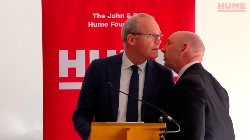 Simon Coveney, being ushered from the room due to a security alert
