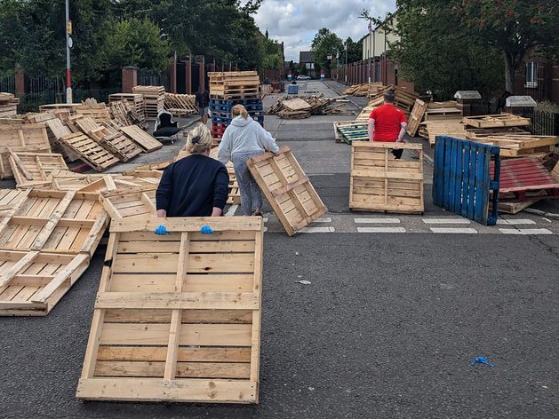 Last-minute bonfire build underway at Belfast peace line as locals defy UVF and UDA