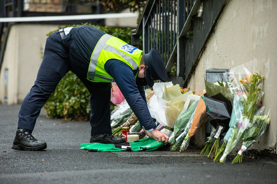 A member of An Garda Síochána lays an Erin's Isle GAA club jersey at Melville Drive, Finglas where Jennie Poole was found with fatal injuries. Photo: Mark Condren