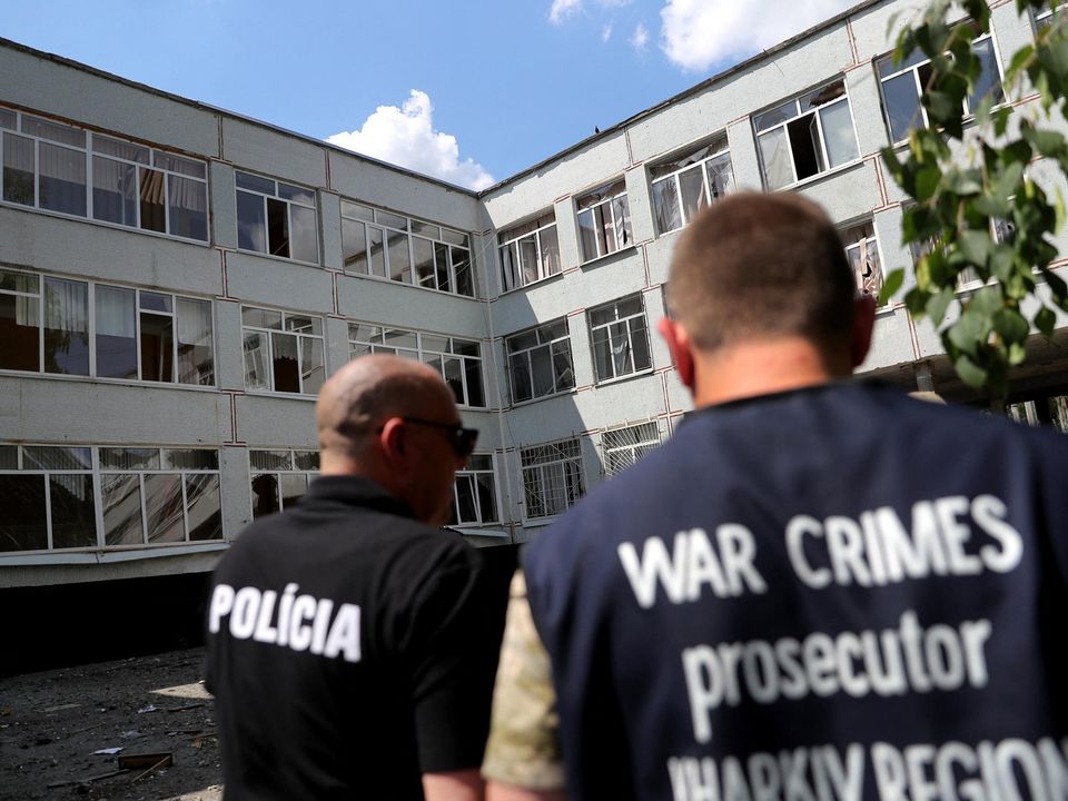 A policeman and a prosecutor's office member arrive at a damaged school after a missile strike at a residential area in Kharkiv