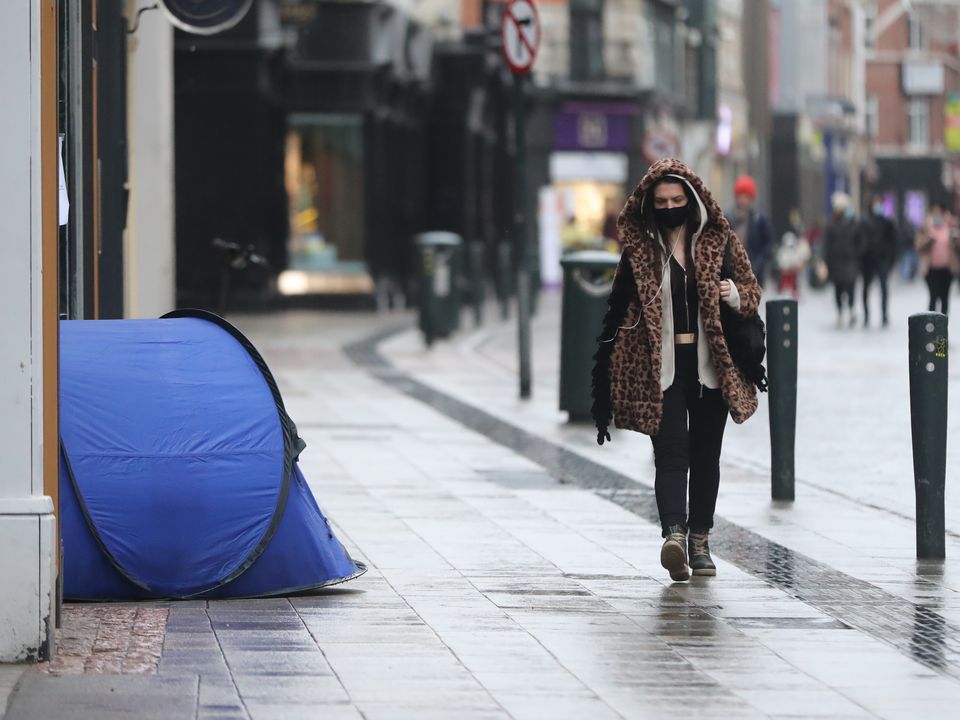 A woman walks past the tent of a homeless person on Grafton Street in Dublin city centre