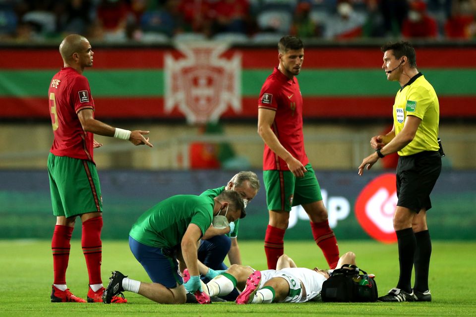 Republic of Ireland defender Dara O’Shea receives treatment on the pitch after fracturing his ankle against Portugal (Isabel Infantes/PA)