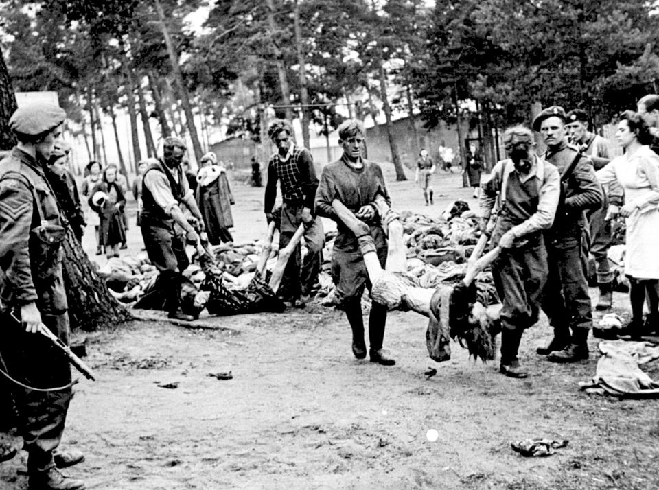 SS men captured at Belsen Concentration Camp, Germany are forced by allied troops to carry the dead bodies of their victims