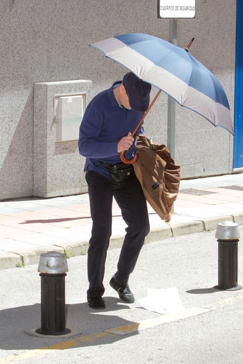 Kinahan Snr stumbles and drops documents as he emerges from court, using an umbrella as a shield