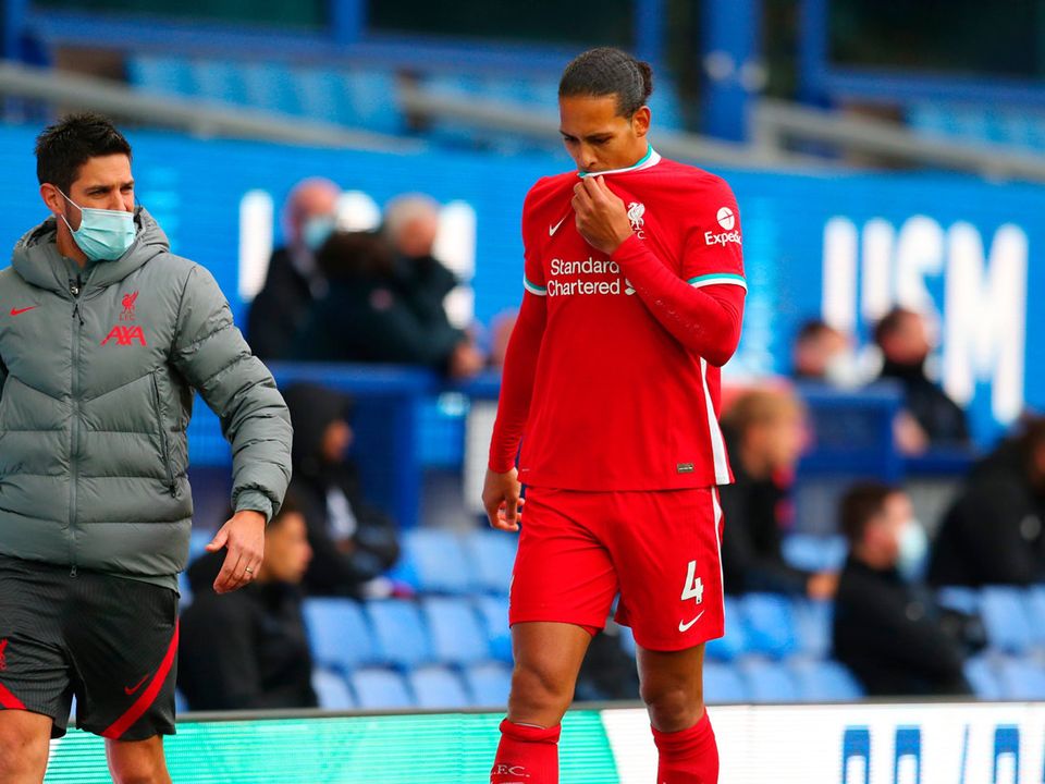Van Dijk leaves the pitch with a member of Liverpool’s medical team. Photo: Catherine Ivill/Getty Images