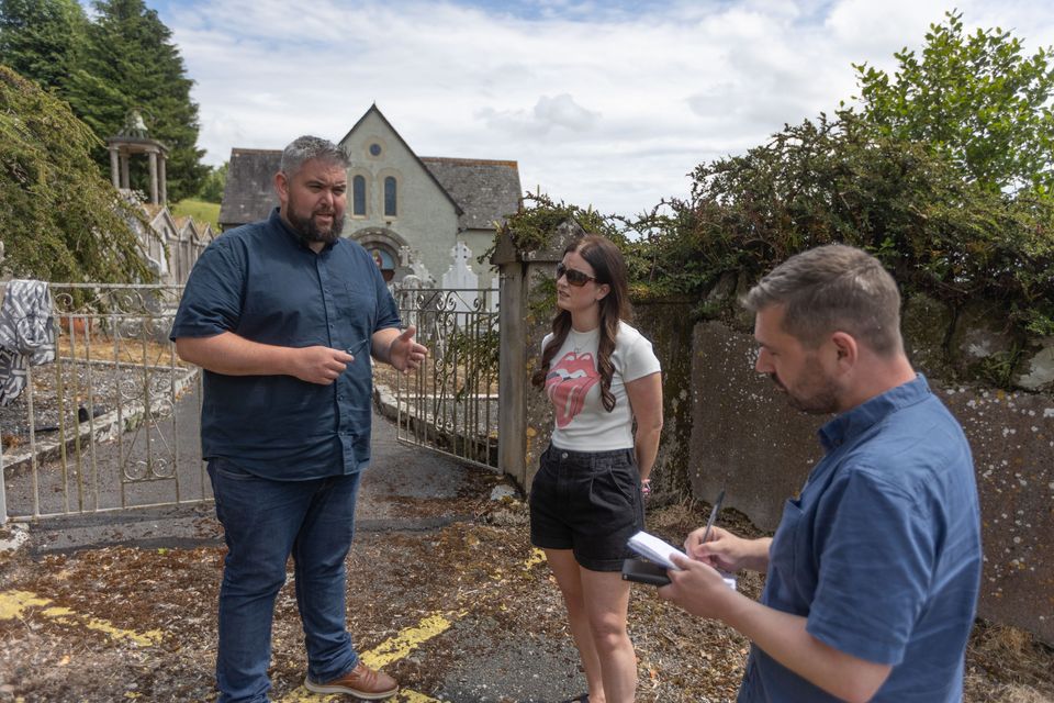 Councilor Conor McGuinness and resident Ailish Hickey talking to reporter Alan Sherry near the church and house