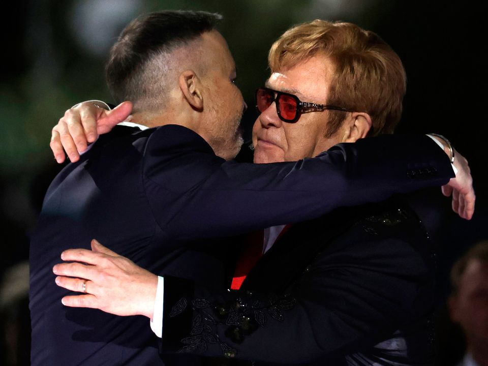 Sir Elton John (R) and his husband David Furnish (L) embrace each other after he was presented with the National Humanities Medal by U.S. President Joe Biden