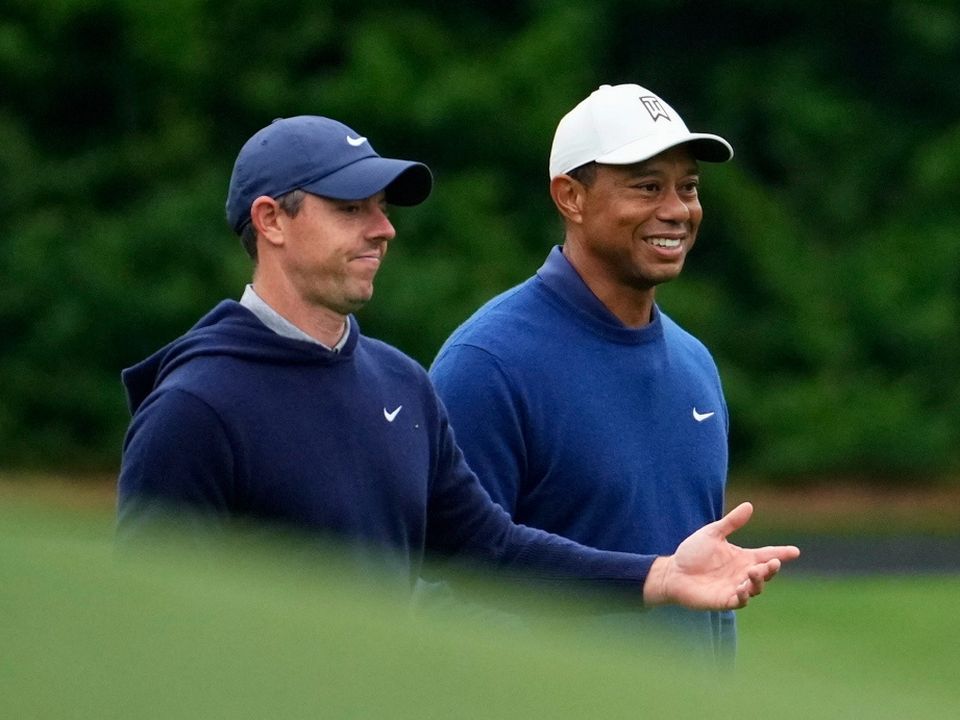 Rory McIlroy and Tiger Woods walk on the 11th fairway during a practice for the Masters