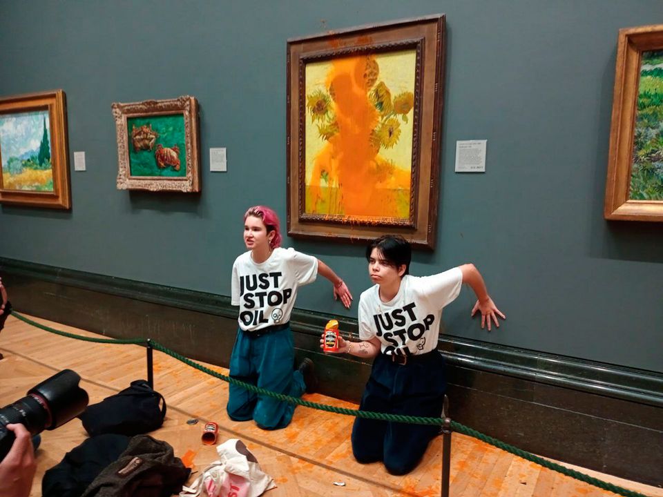 Two protesters after throwing tinned soup at Vincent Van Gogh's famous 1888 work Sunflowers at the National Gallery in London. Photo: Just Stop Oil/PA Wire 