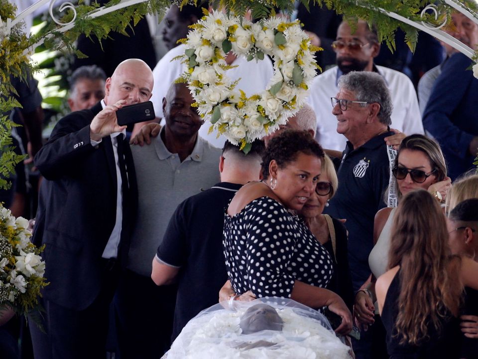 FIFA president Gianni Infantino takes a selfie, and Pele's daughter, Kelly Cristina Nascimento is pictured with mourners as the body of Brazilian soccer legend Pele is seen in his casket, as he lays in state on the pitch of his former club Santos' Vila Belmiro stadium