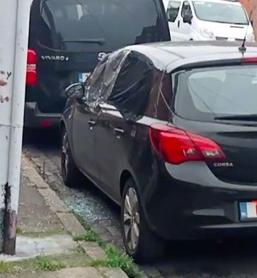 Du verre brisé est visible au sol à côté de cette voiture