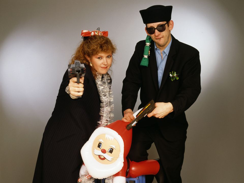 Singers Kirsty MacColl (1959 - 2000) and Shane MacGowan with toy guns and an inflatable Santa in a festive scenario, circa 1987. In 1987, the pair collaborated on the Pogues' Christmas song 'Fairytale of New York'. (Photo by Tim Roney/Getty Images)