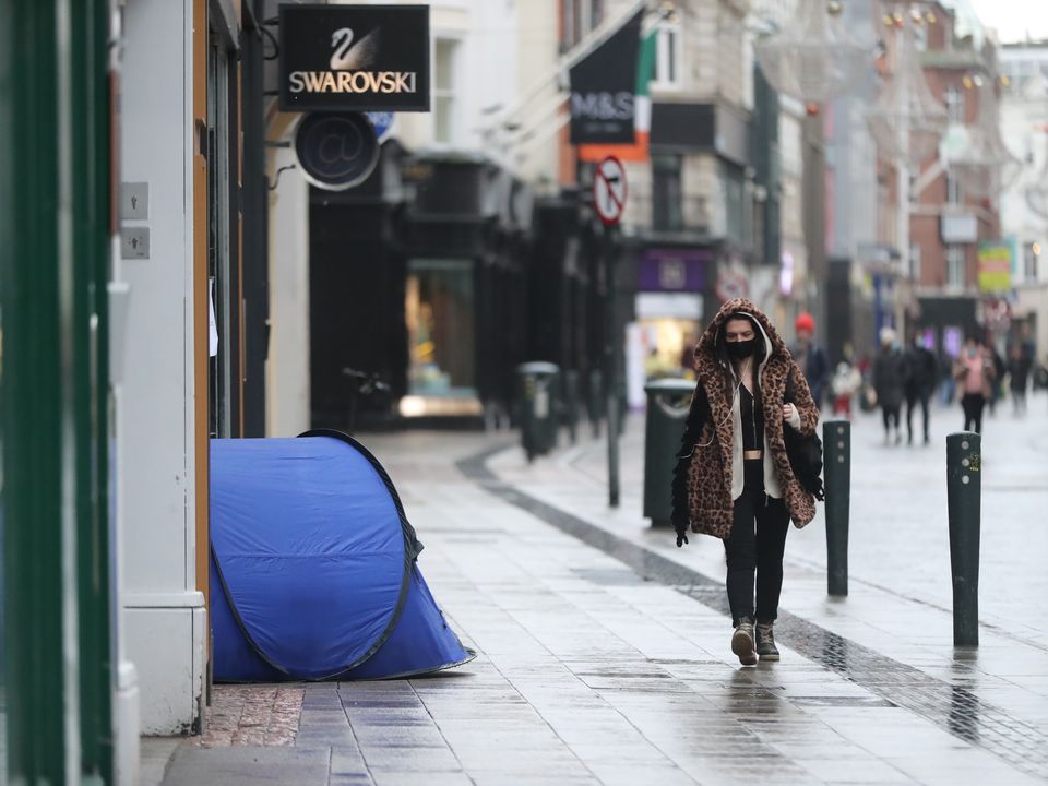A woman walks past the tent of a homeless person on Grafton Street in Dublin city centre as Ireland remains in lockdown to help prevent the spread of coronavirus. Ireland's health service is potentially facing the most challenging week in its history with the number of Covid-19 patients requiring intensive care treatment having risen sharply since the end of December. Picture date: Monday January 18, 2021.