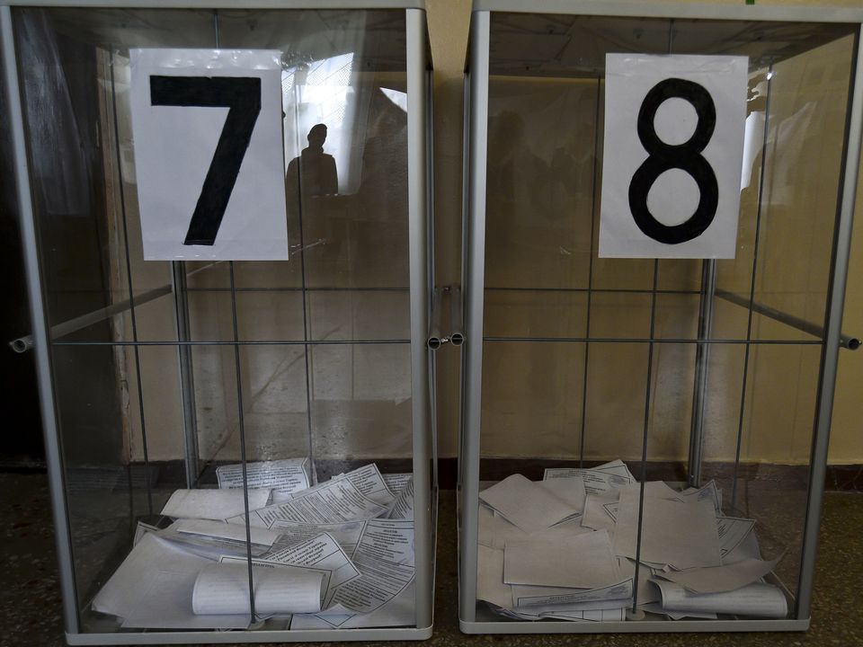 A voter is reflected in a ballot box at a polling station during a referendum in Melitopol, Zaporizhzhia region, southern Ukraine, Tuesday, Sept. 27, 2022.