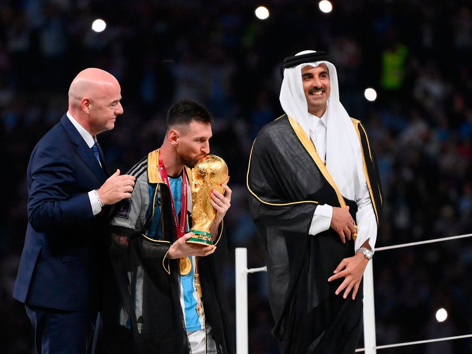 Lionel Messi of Argentina kisses the FIFA World Cup Qatar 2022 Winner's Trophy as Gianni Infantino, President of FIFA, and Sheikh Tamim bin Hamad Al Thani, Emir of Qatar, look on. (Getty)